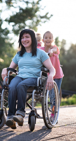 Eine Tochter schiebt ihre Mutter im Rollstuhl